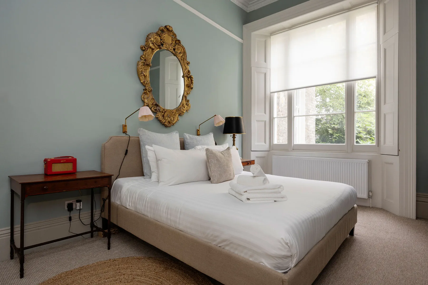 Dormitorio con una cama bien tendida junto a una ventana grande.