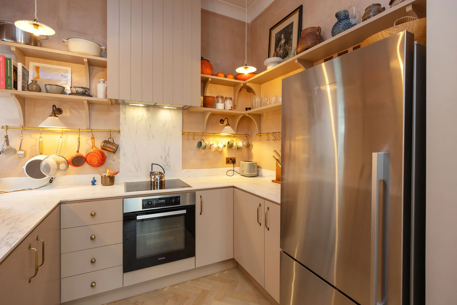 Una cocina de tonos cálidos con estufa, encimera y refrigerador de acero inoxidable.
