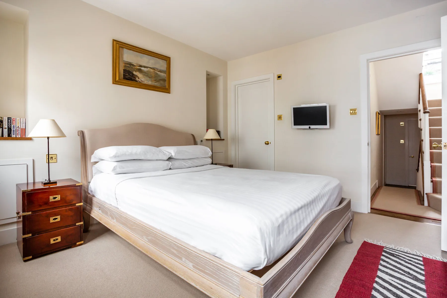 A bedroom with a neatly made bed and a television mounted on the wall.