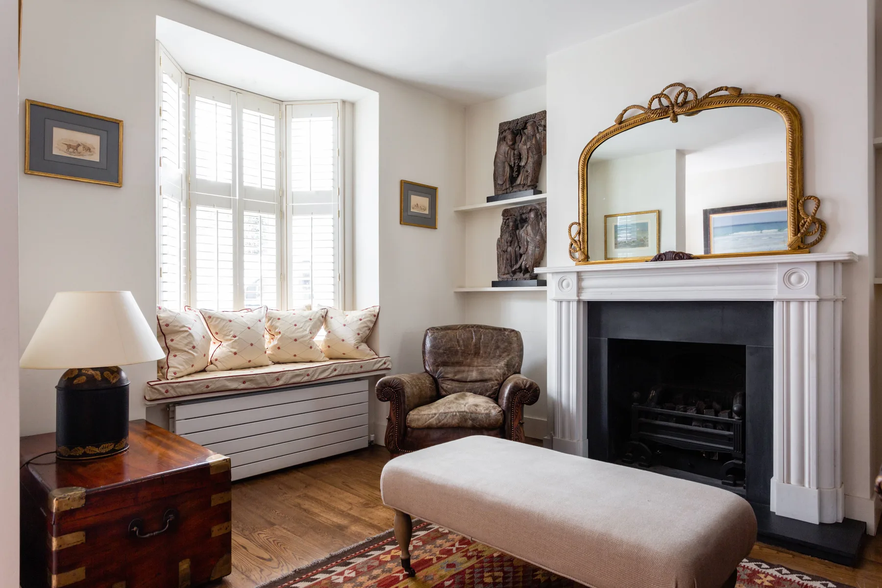 A bright living room with a window seat and fireplace.