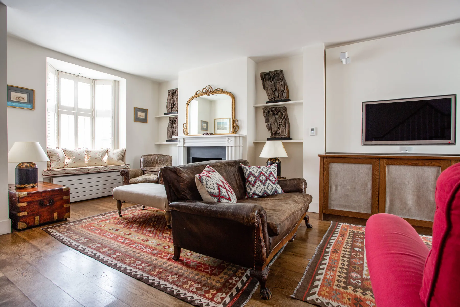 A bright living room with seating arranged around a fireplace and television.
