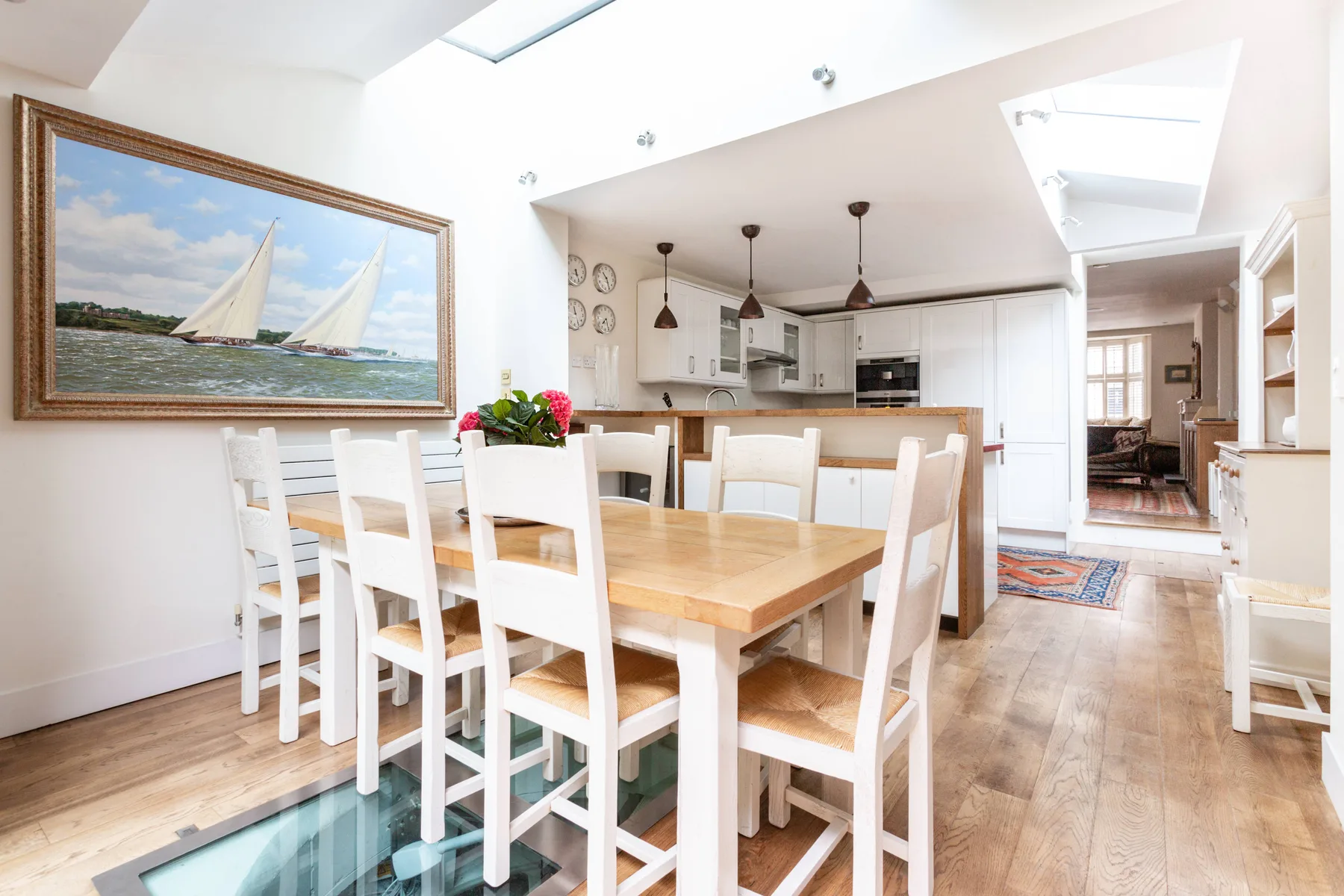A bright dining area with a wooden table and white seating beside the kitchen.