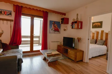 A living room with seating, a television, and glass doors opening to a balcony.