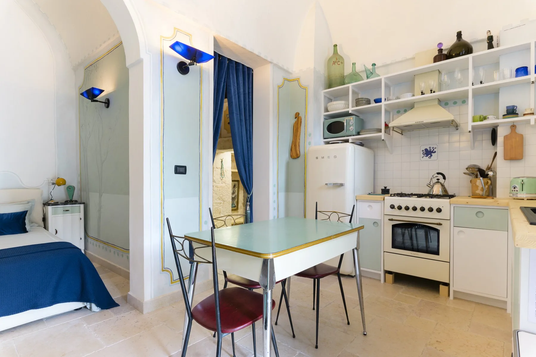 Un espacio combinado de dormitorio y cocina con una mesa de comedor y estanterías.