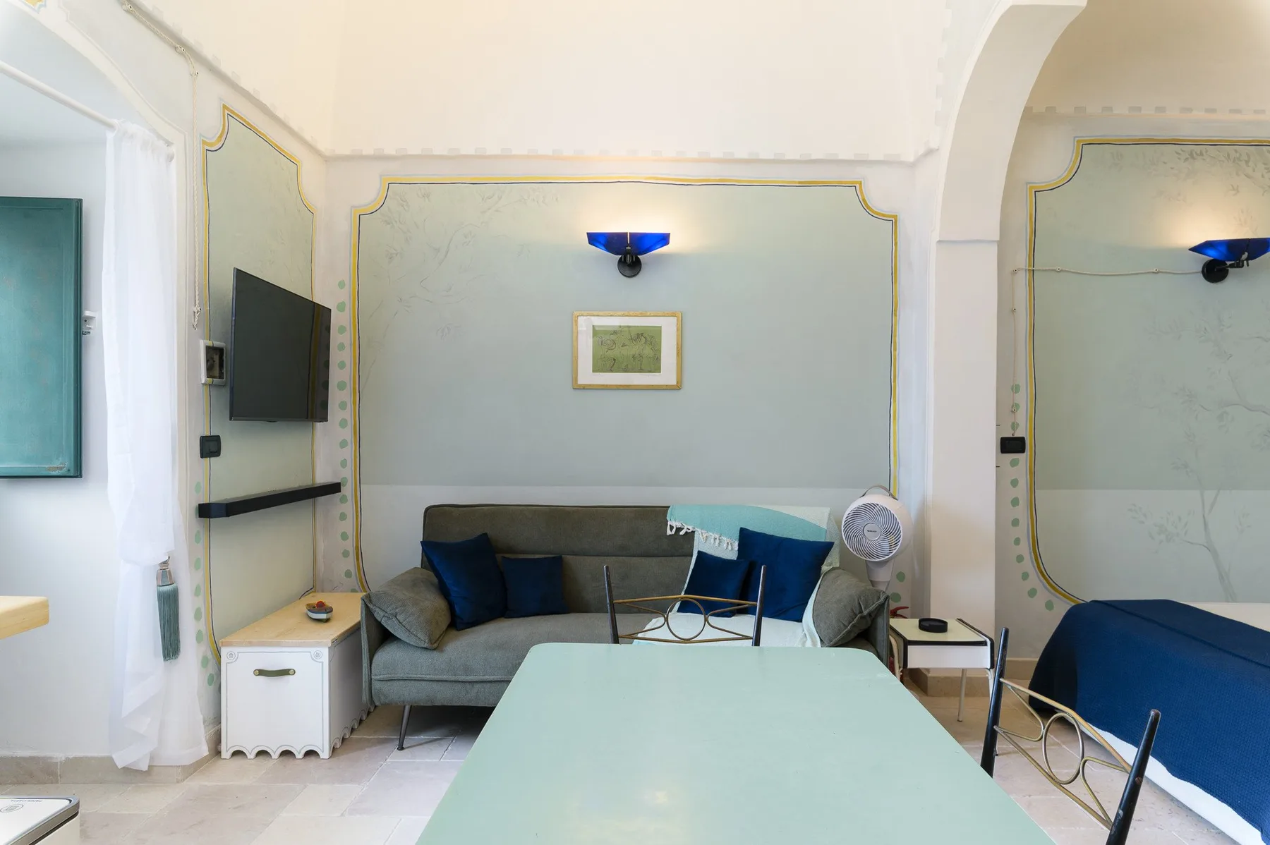 Una sala de estar con asientos alrededor de una mesa baja y un televisor en la pared.