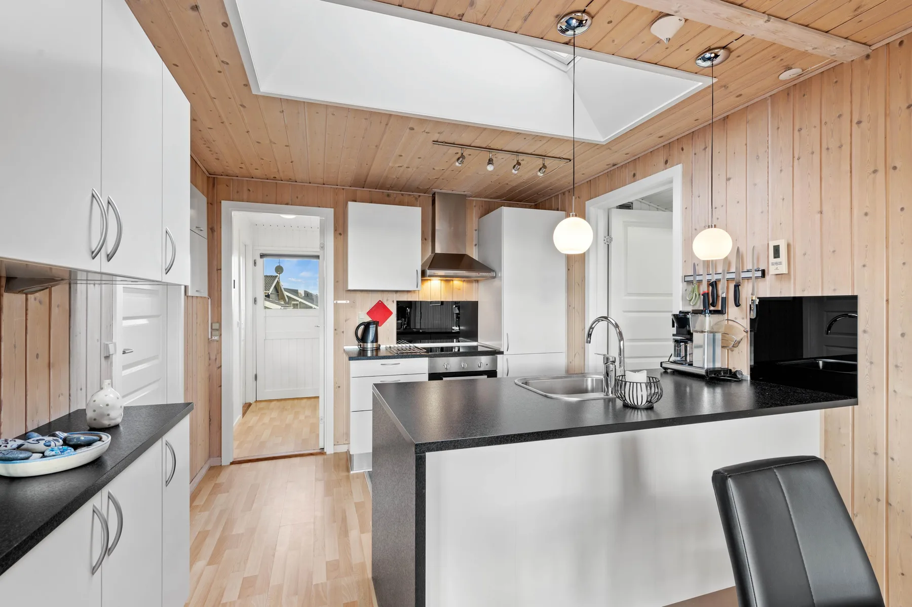 Una cocina luminosa con una isla central y paredes revestidas de madera.