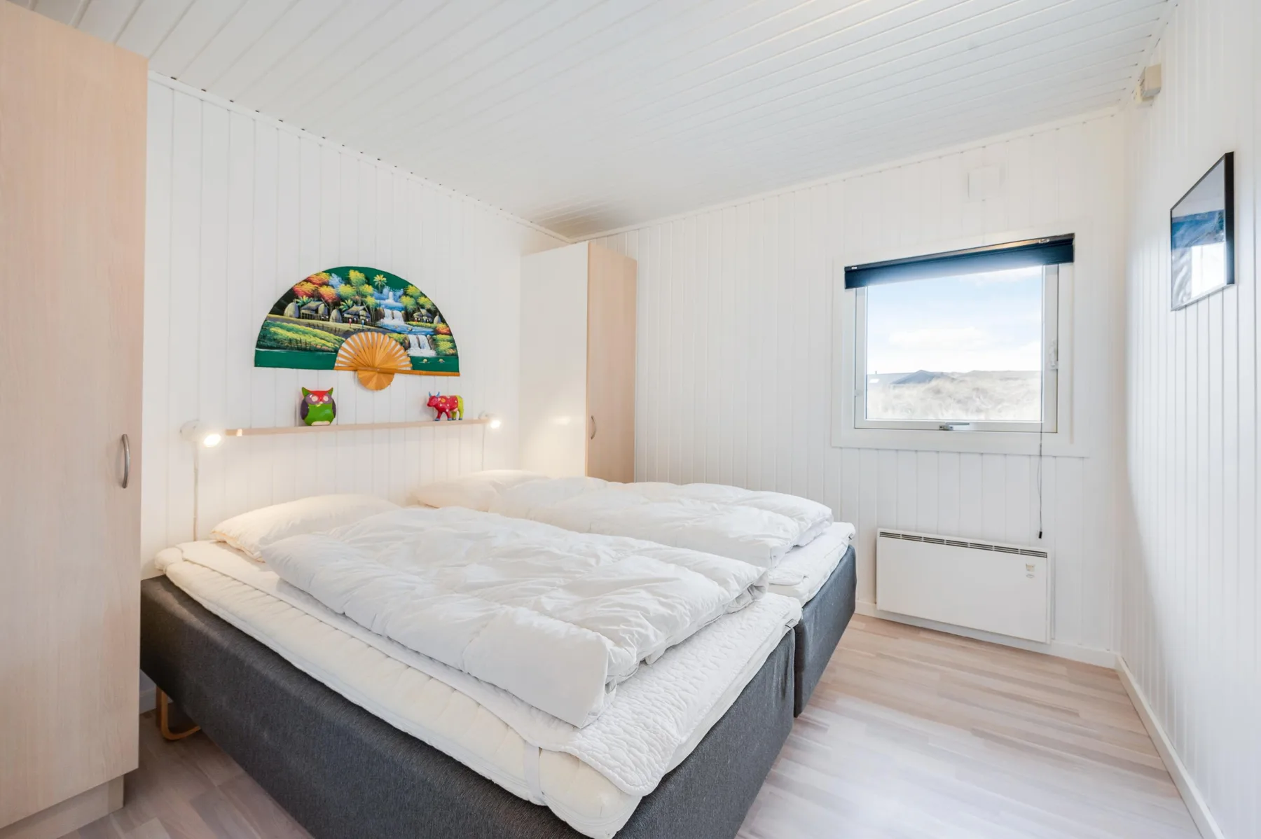 Un dormitorio luminoso con una cama bajo una decoración colorida en la pared.