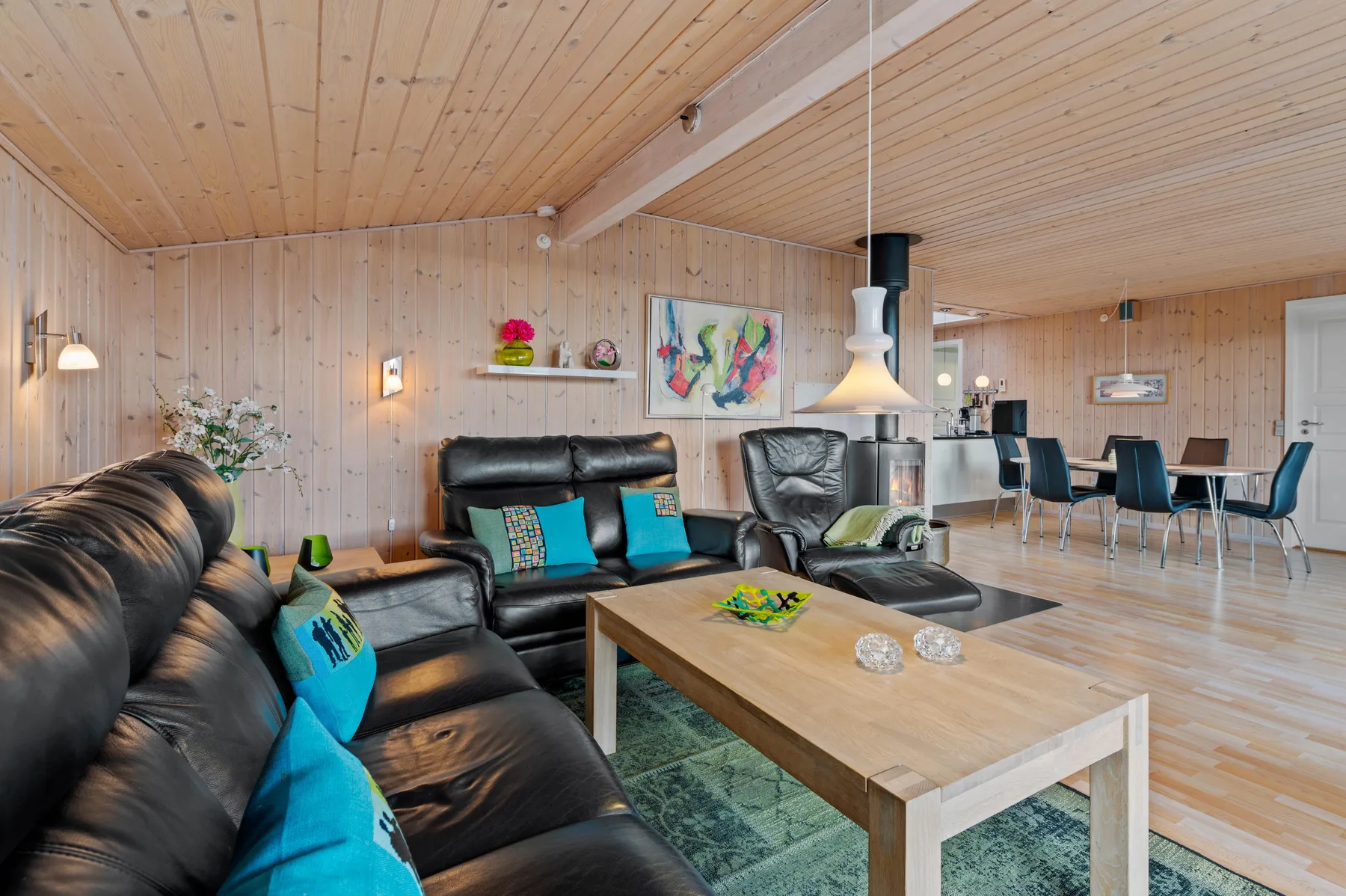 Una sala de estar con asientos de cuero y una mesa de centro de madera, con un comedor al fondo.