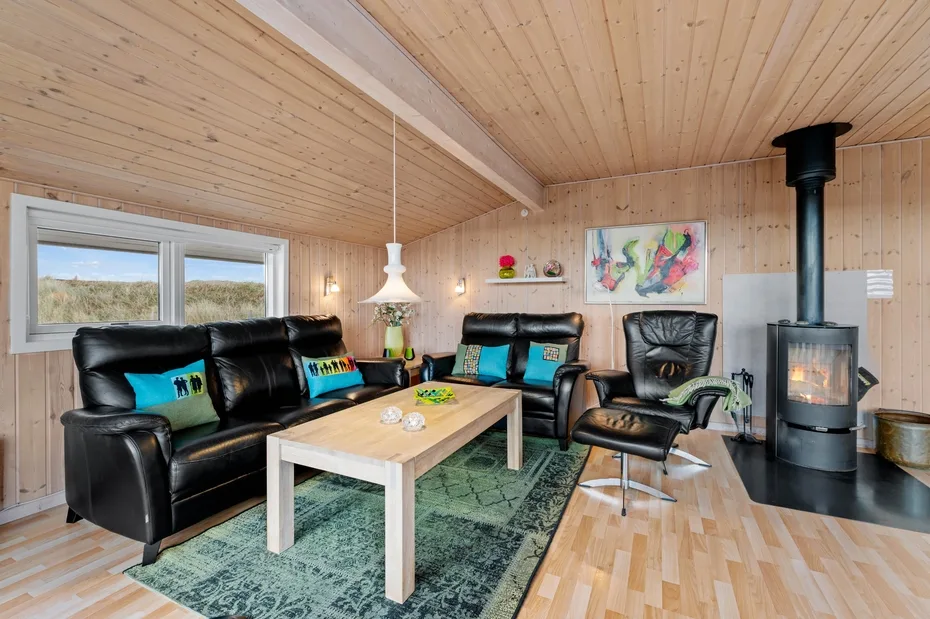 Una sala con paneles de madera, asientos alrededor de una mesa de centro y una estufa.