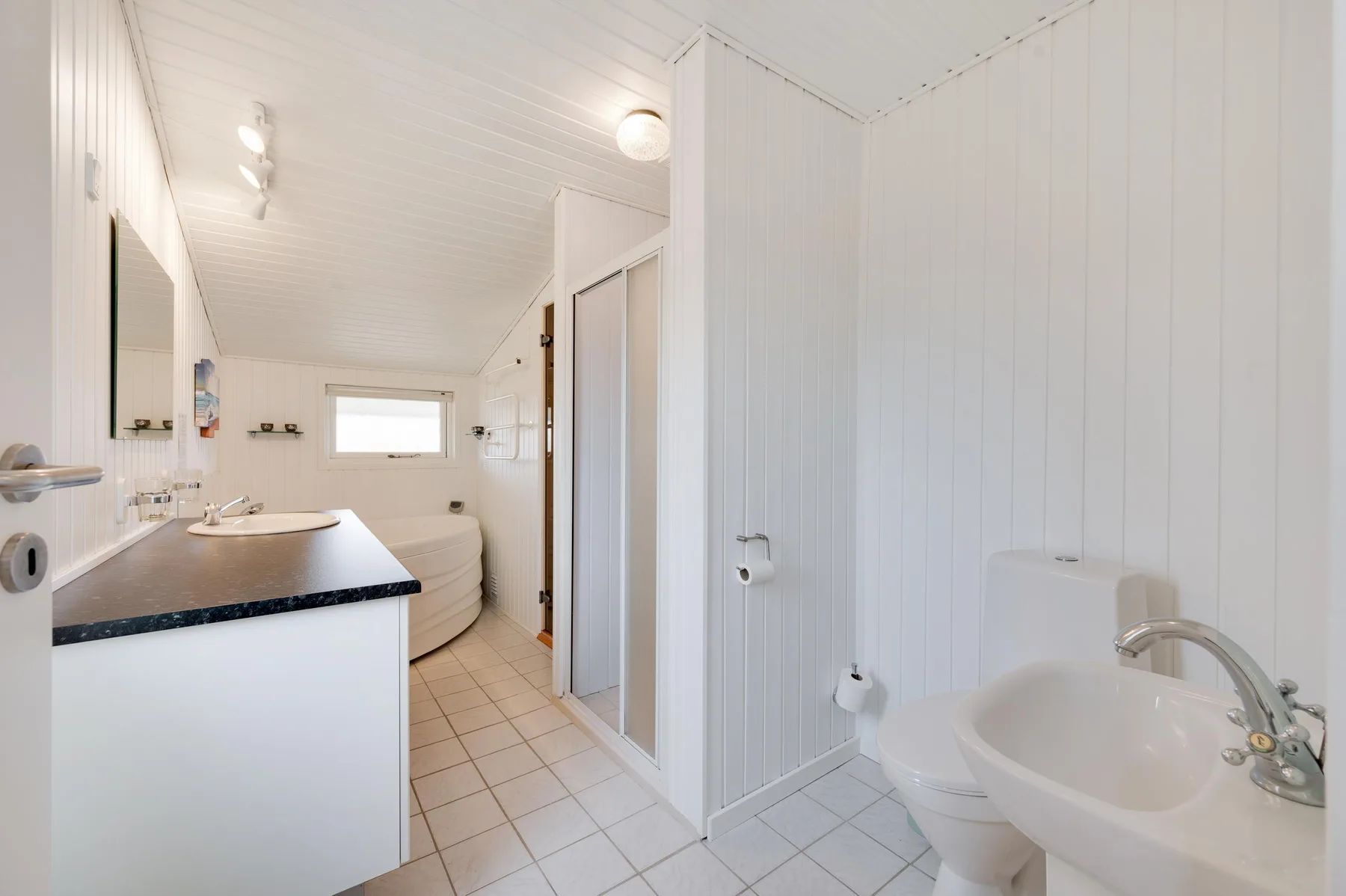 Un baño luminoso con lavabo, inodoro y bañera.