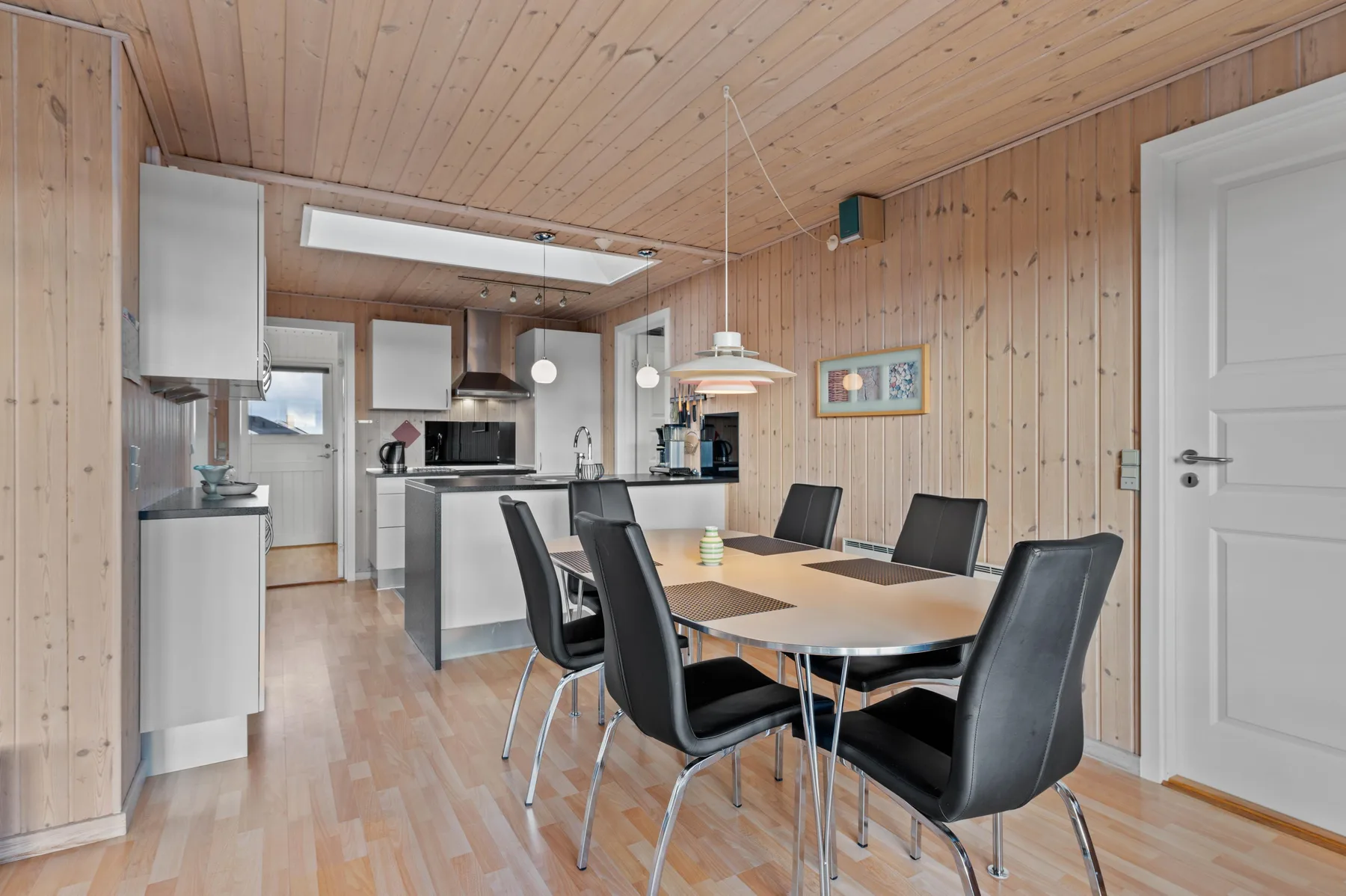 Comedor con una mesa y sillas junto a una cocina abierta.