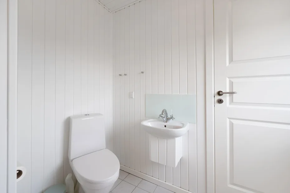 Un baño luminoso con un inodoro y un lavabo montado en la pared.