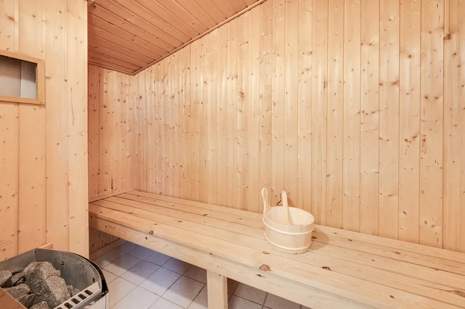 Una sauna revestida de madera con un banco largo y un cubo.