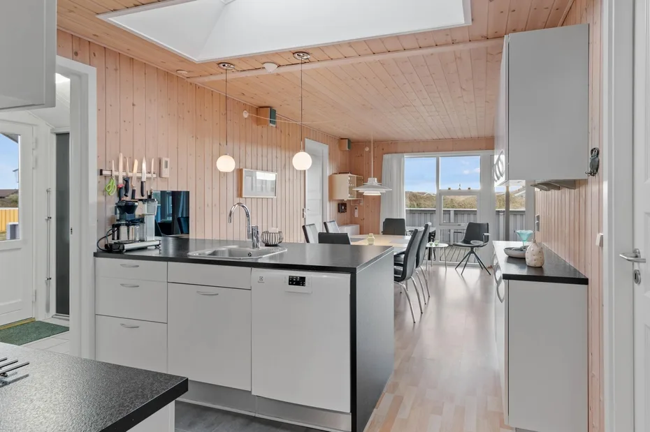 Una cocina luminosa con una isla central y asientos junto a las ventanas.