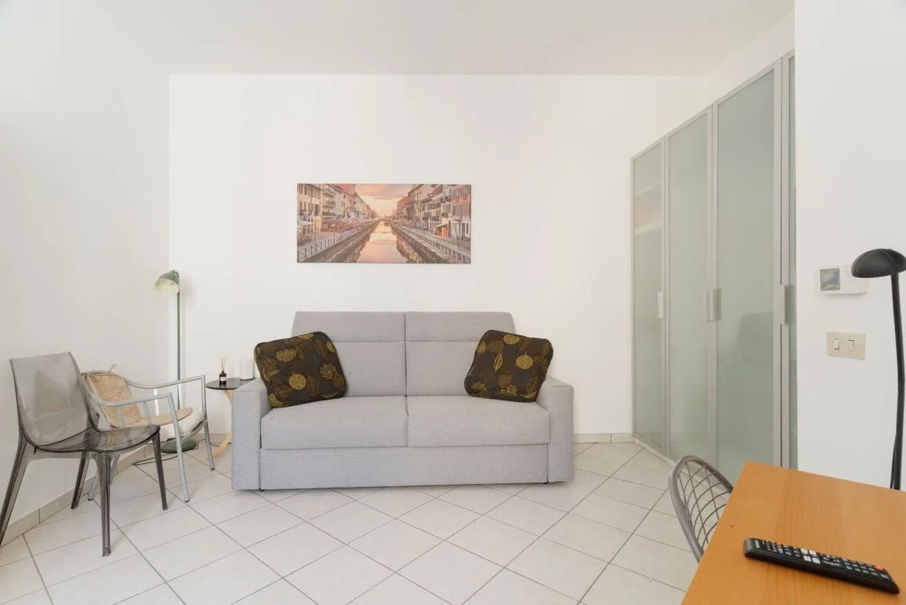 A bright living room with a gray sofa and framed artwork on the wall.