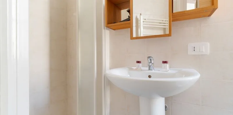 A bathroom sink beneath a wall mirror, with a tiled wall.