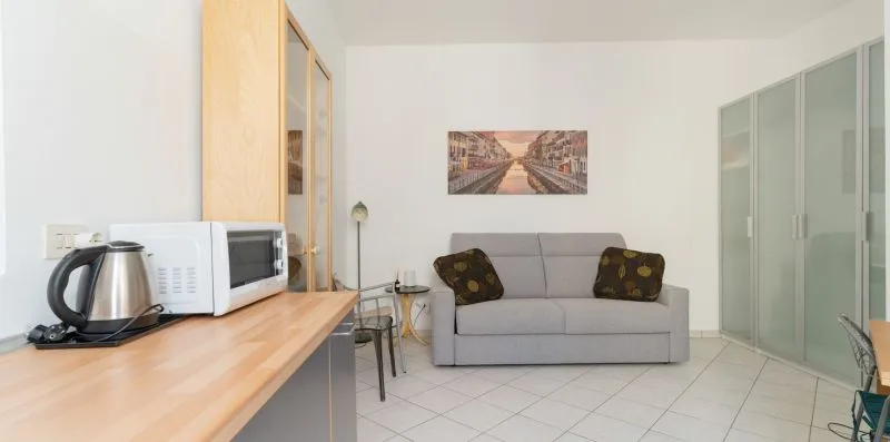A bright living area with a gray sofa, a wooden counter, and glass doors.