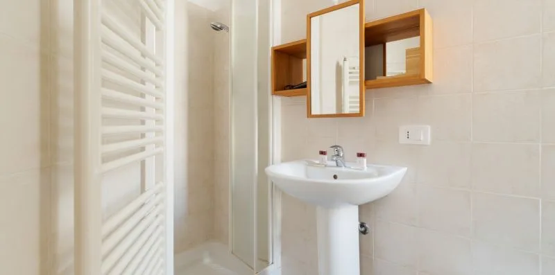 A bright bathroom with a sink, mirror, and glass shower.