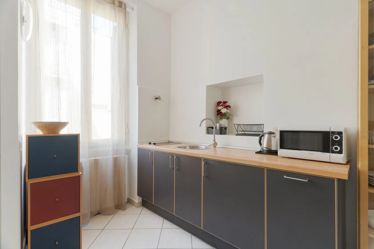 A compact kitchen with dark cabinets, a countertop, and a microwave.
