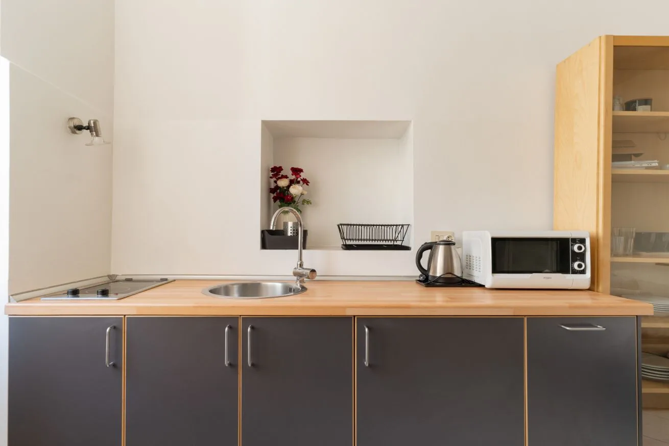 A kitchen counter with a sink, microwave, and dark lower cabinets.