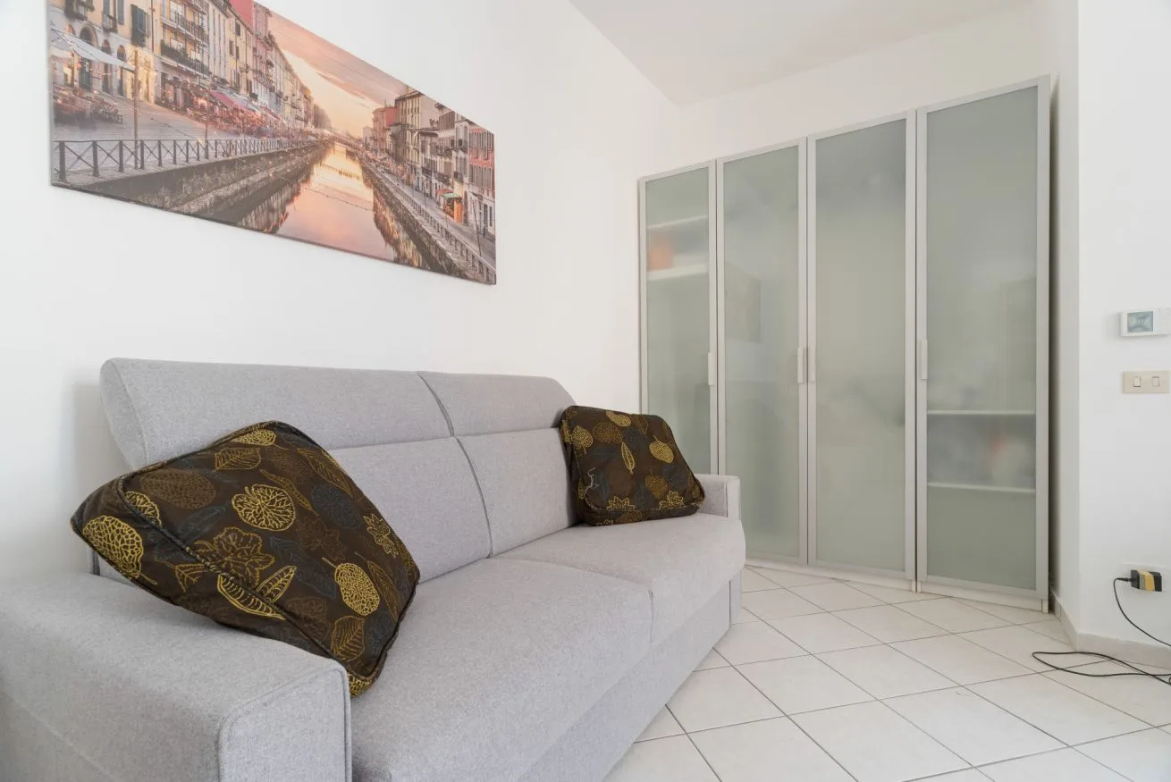 A living room with a light-colored sofa and a large wall print.
