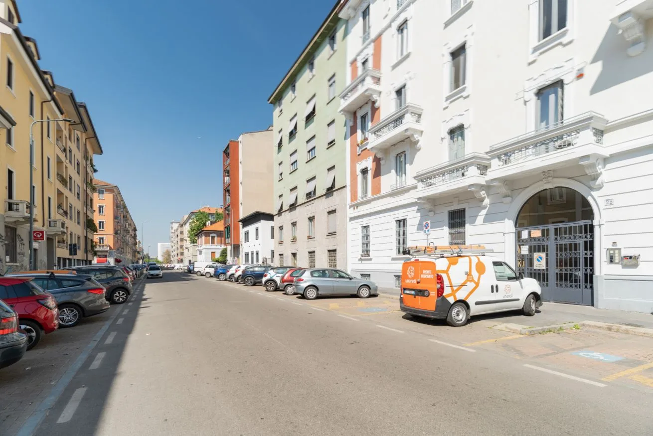 An urban street lined with apartment buildings and parked cars.