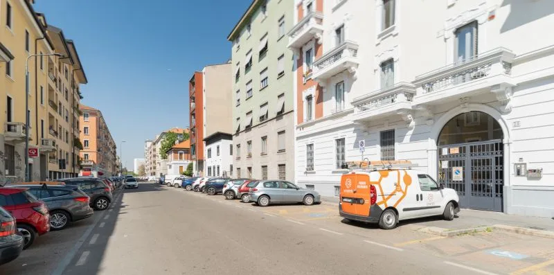 A city street lined with apartment buildings and parked cars.