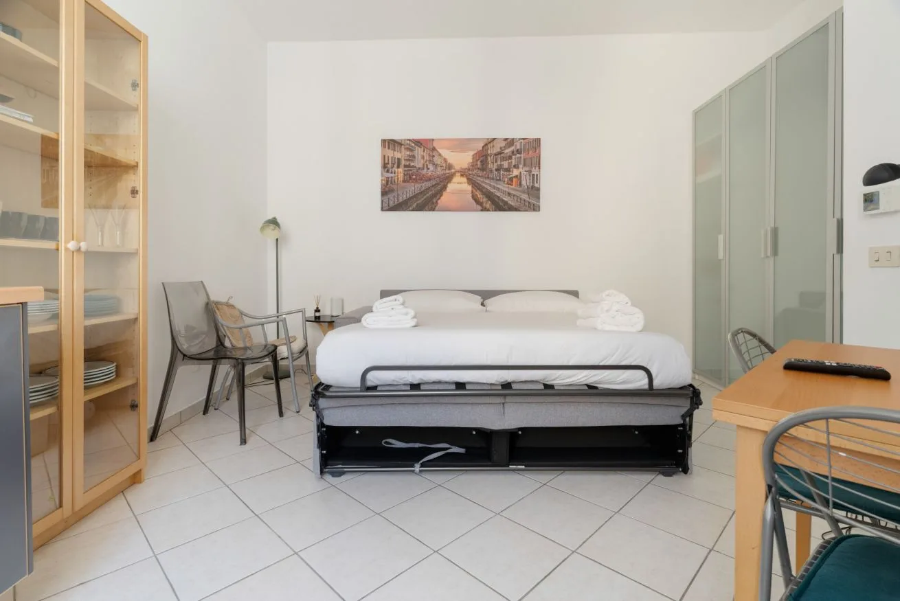 A bedroom with a bed, glass-fronted cabinets, and seating.