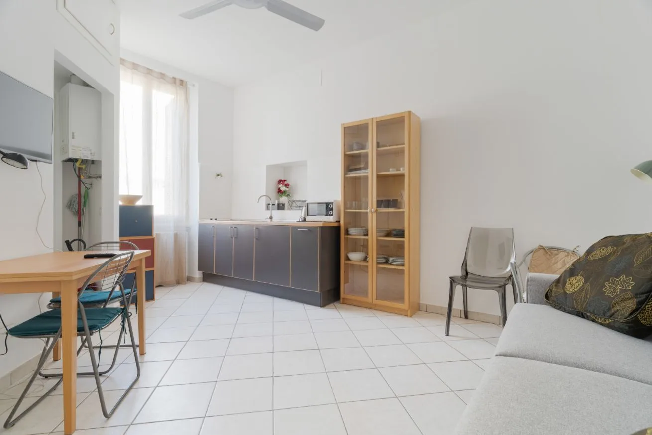 A bright kitchen and dining area with a counter, open shelving, and seating.