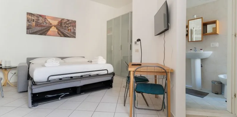 A bedroom with a bed, a desk, and an adjoining bathroom.