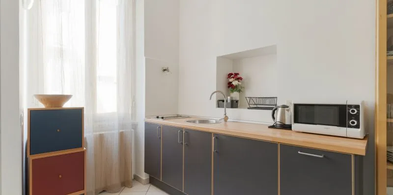 A modern kitchen with dark cabinets, a countertop, and small appliances.