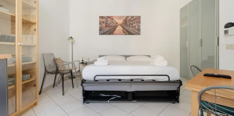 A bedroom with a bed, chairs, and a tall cabinet.