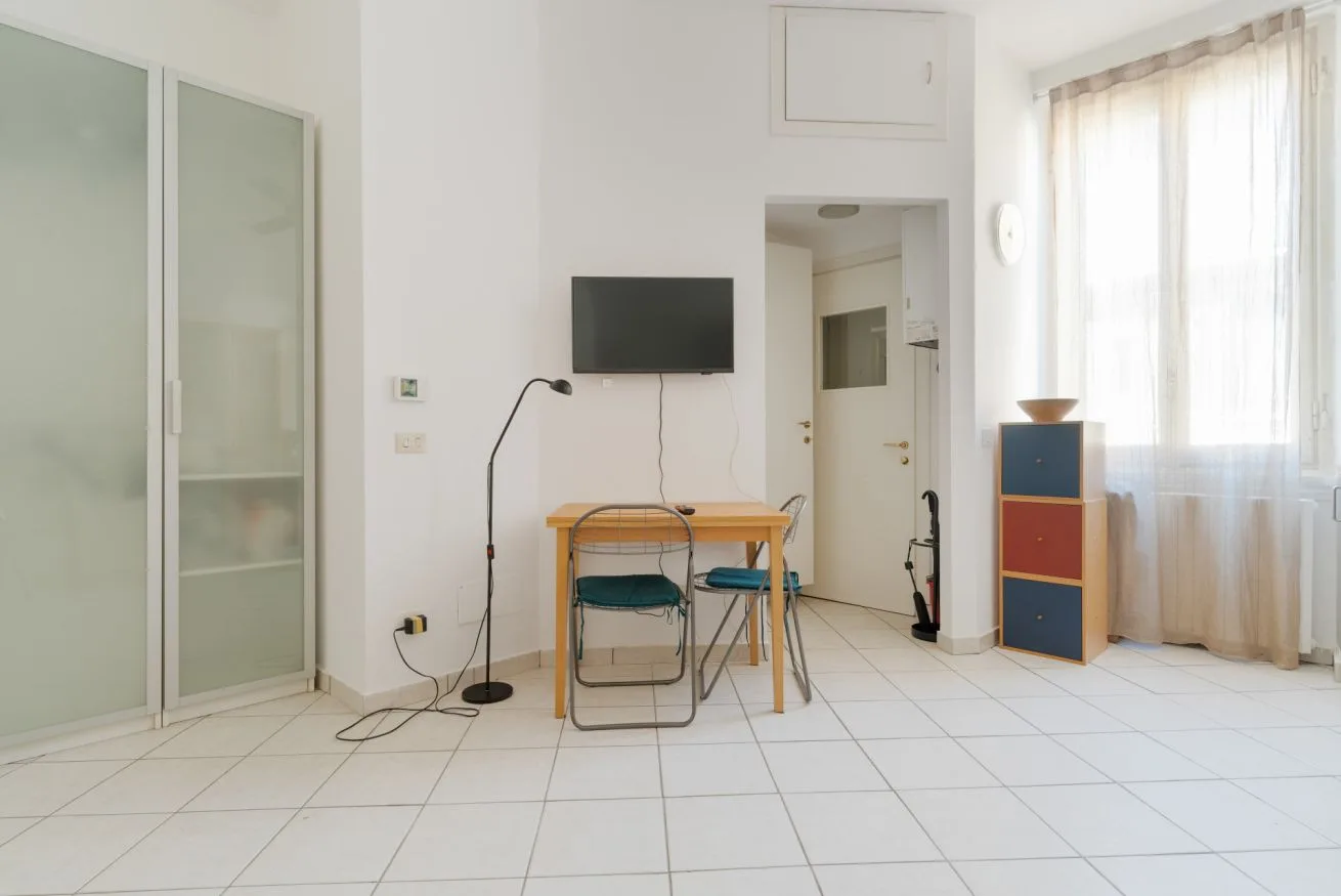 A bright room with a small table and chairs beside a television.