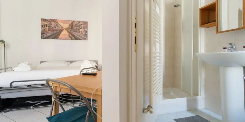 A bedroom with a desk and chair beside an adjoining bathroom.