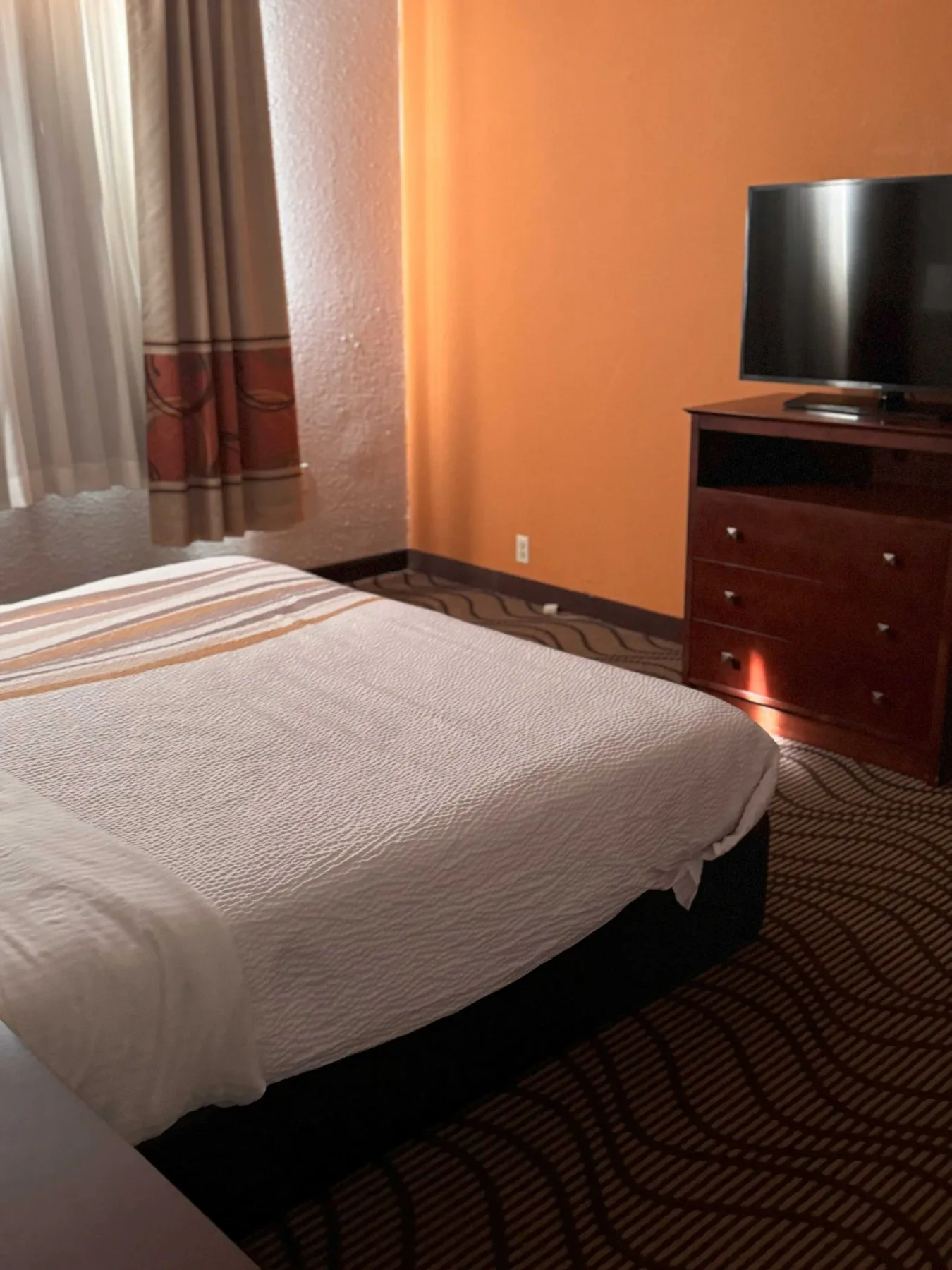 Dormitorio de suite con una cama king size y un televisor de pantalla plana.
