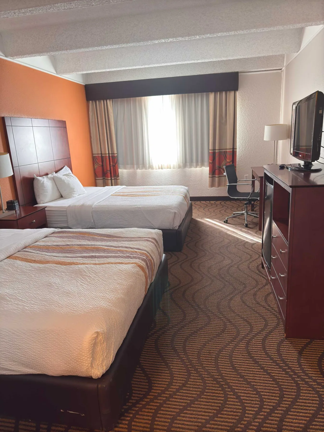 Habitación de hotel con dos camas y un televisor.