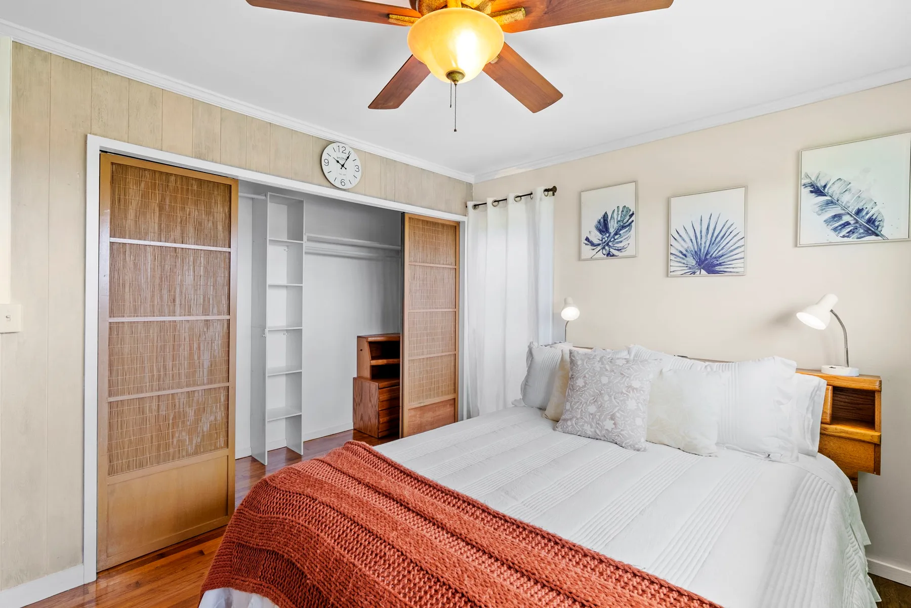 Un dormitorio con una cama bien tendida y un armario empotrado abierto.