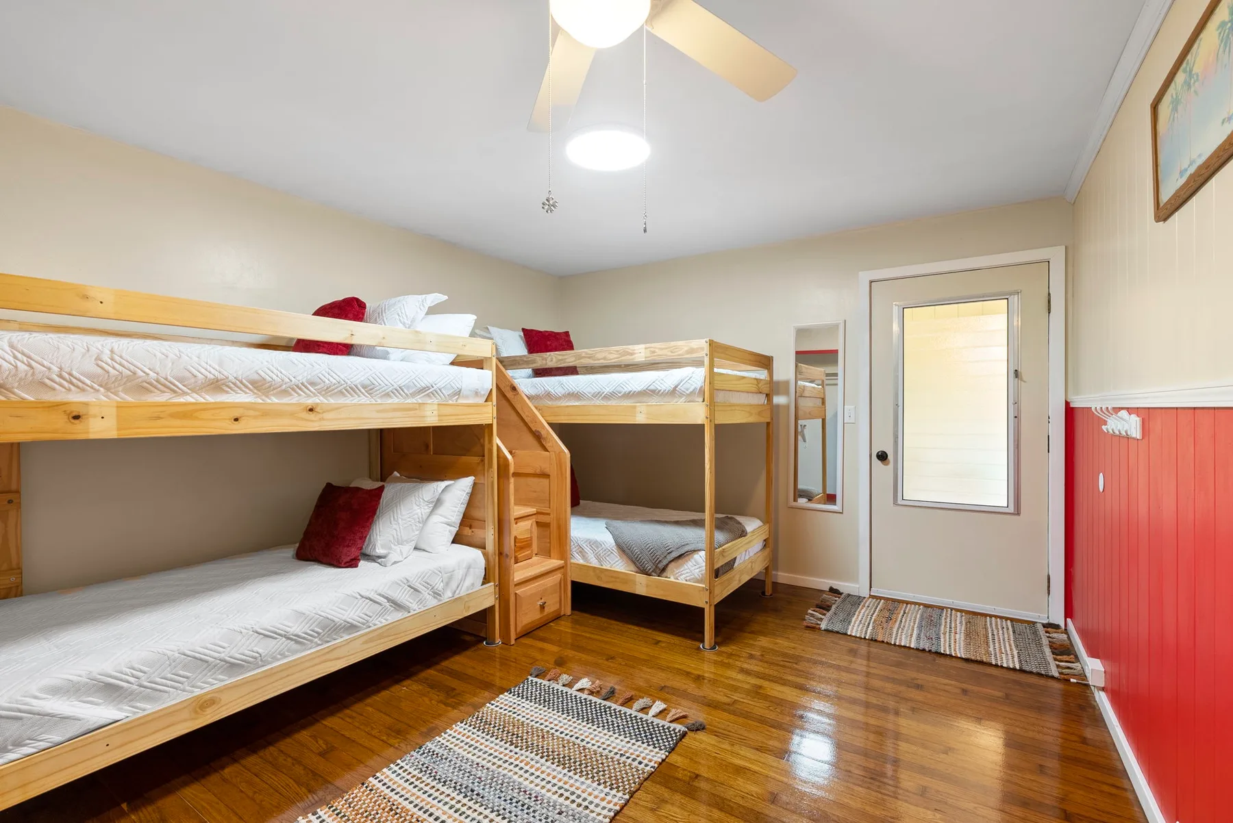 Un dormitorio con literas de madera, ropa de cama blanca y un ventilador de techo.