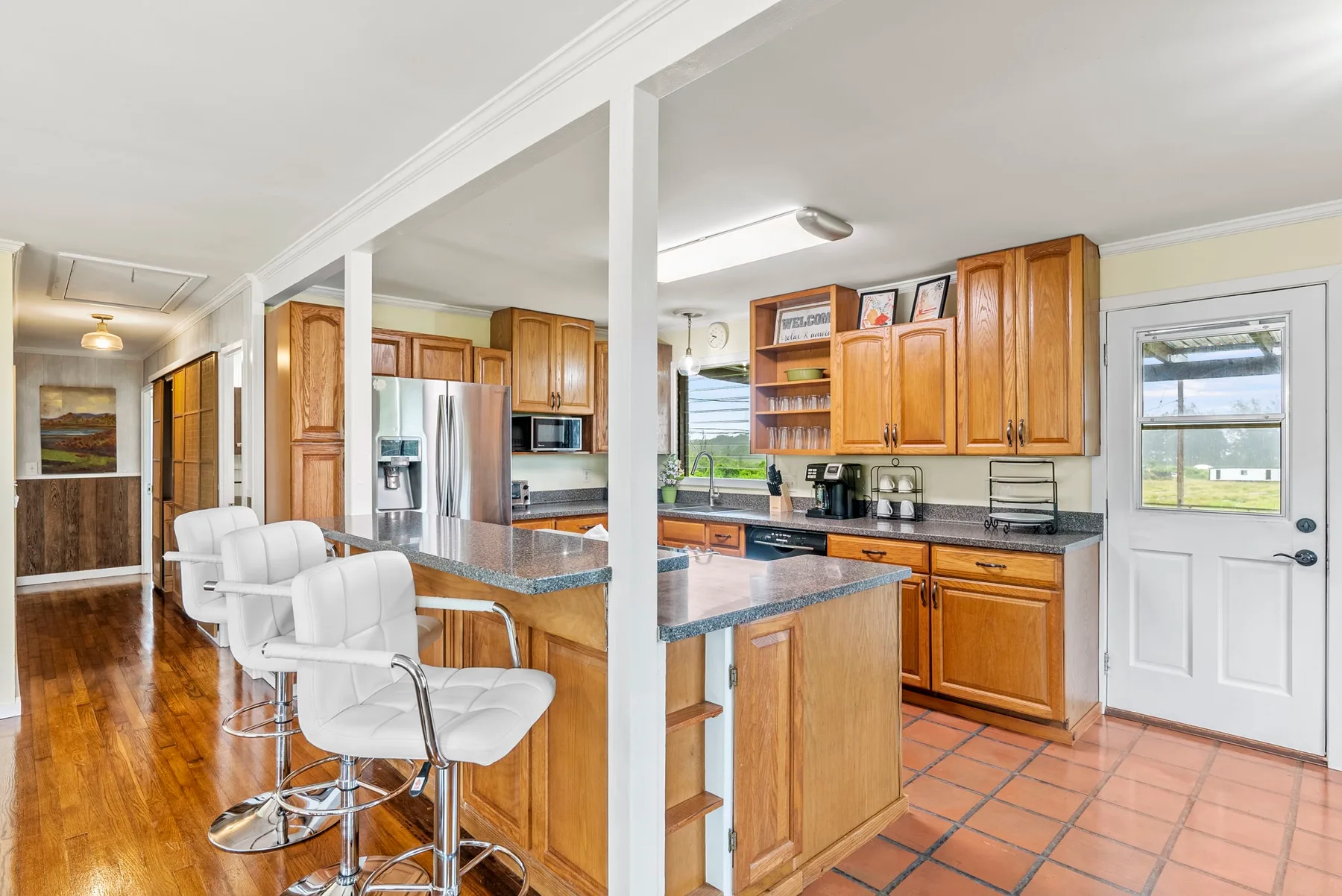 Cocina abierta con gabinetes de madera y una barra para desayunar.