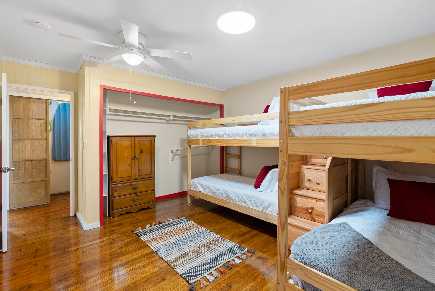 Un dormitorio con literas, una cómoda de madera y suelo de madera pulida.