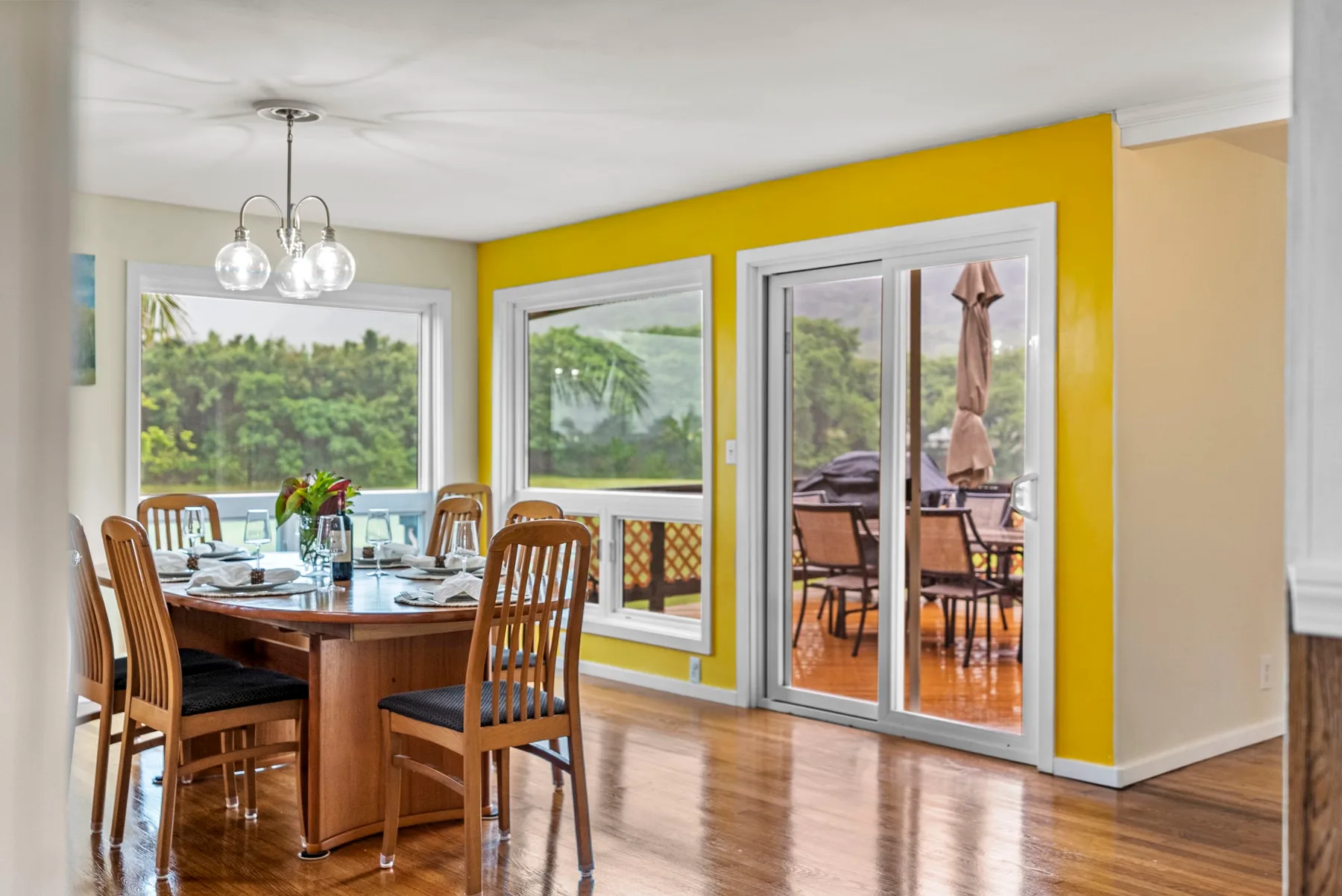 A dining area with a wooden table sits beside glass doors opening to a patio.
