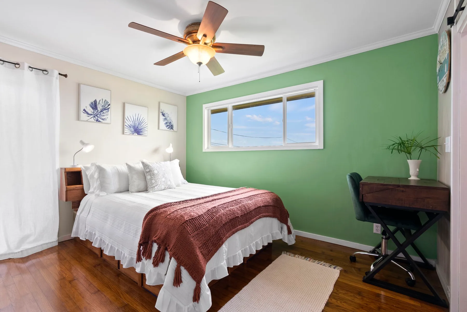 Un dormitorio con una cama bien hecha y una pared verde.