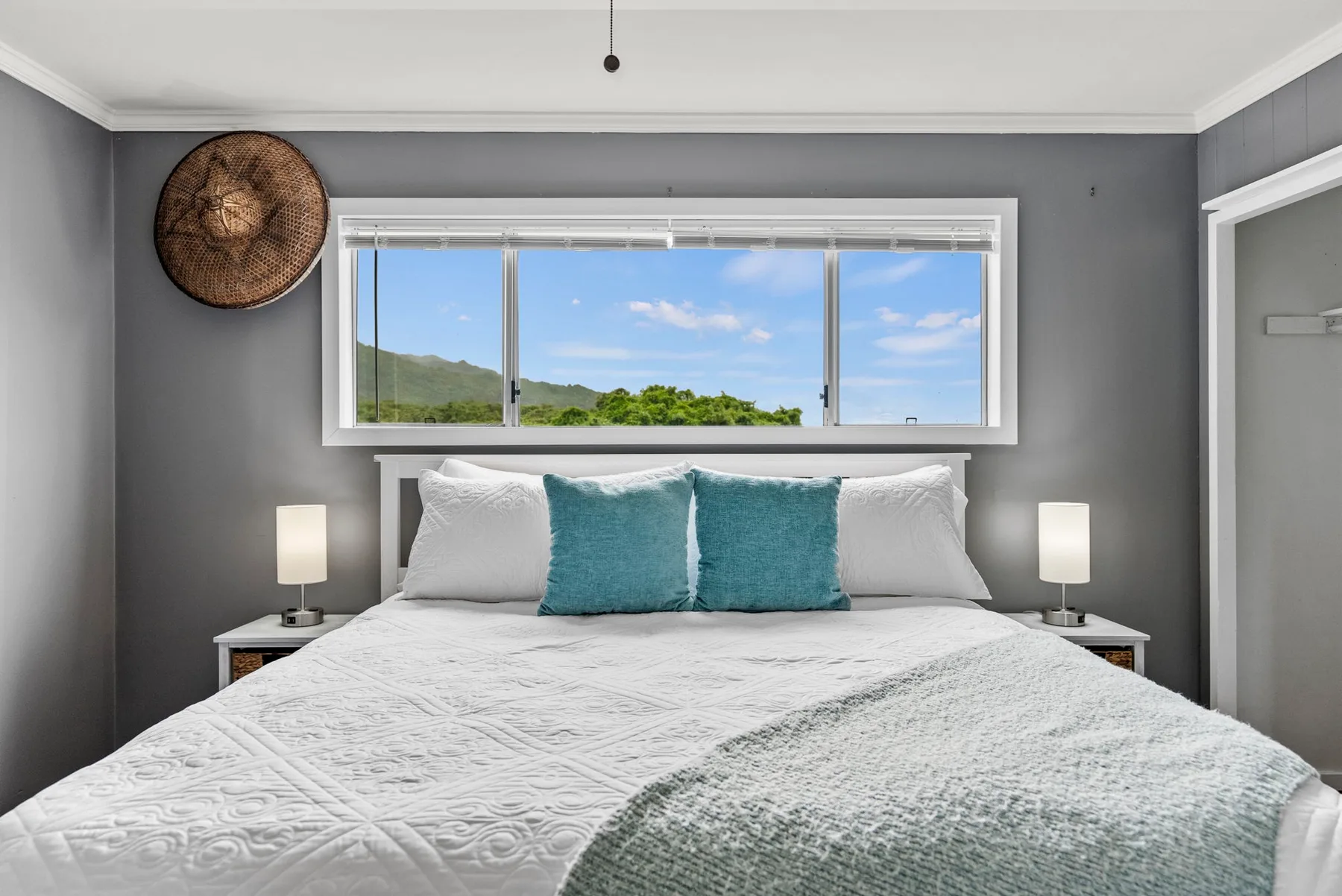 Un dormitorio con una cama bajo una ventana amplia con vistas a la vegetación.