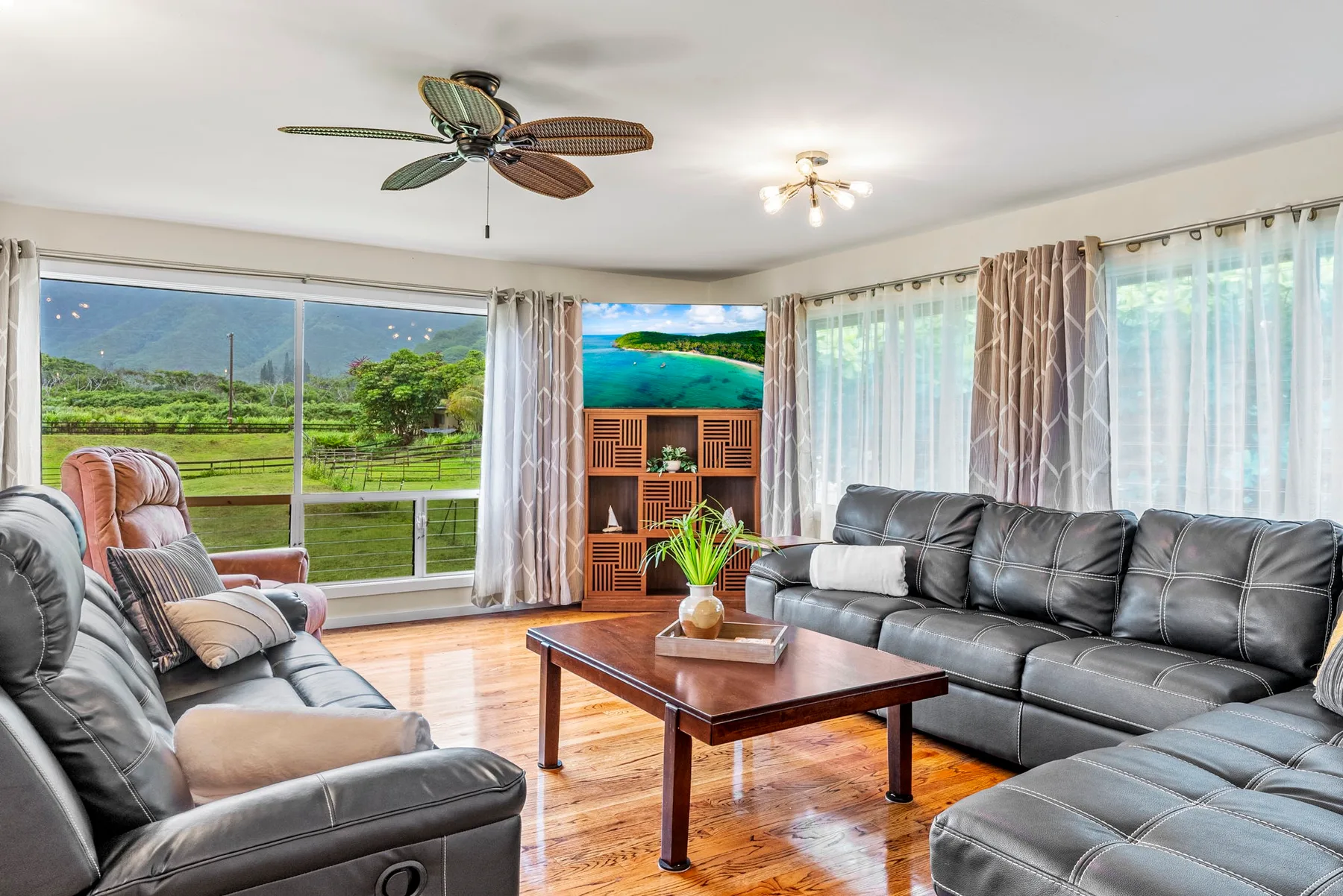 A bright living room with seating around a wooden coffee table and a television.