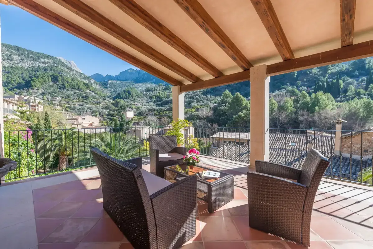 A covered outdoor seating area overlooks a green mountain valley.