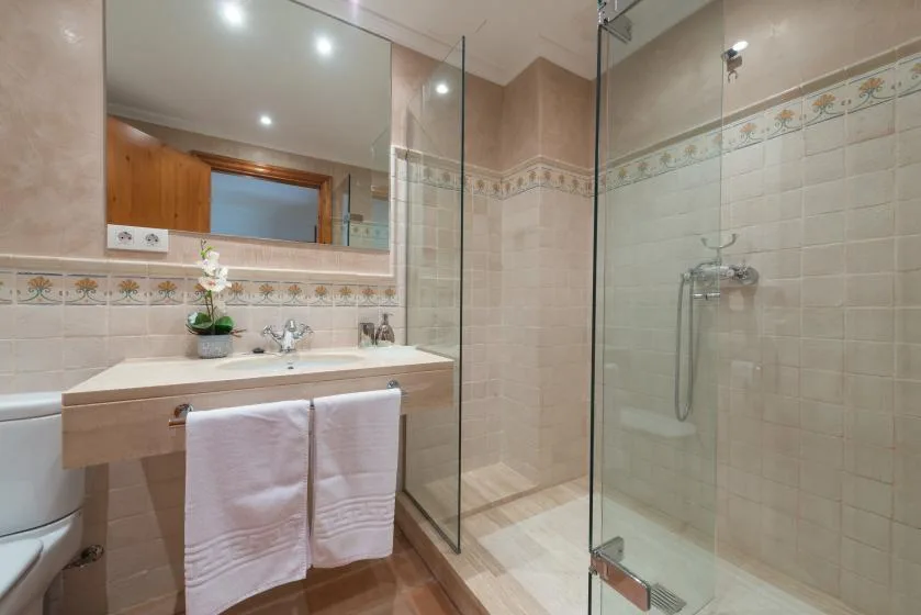 A tiled bathroom with a sink vanity, mirror, and glass shower.