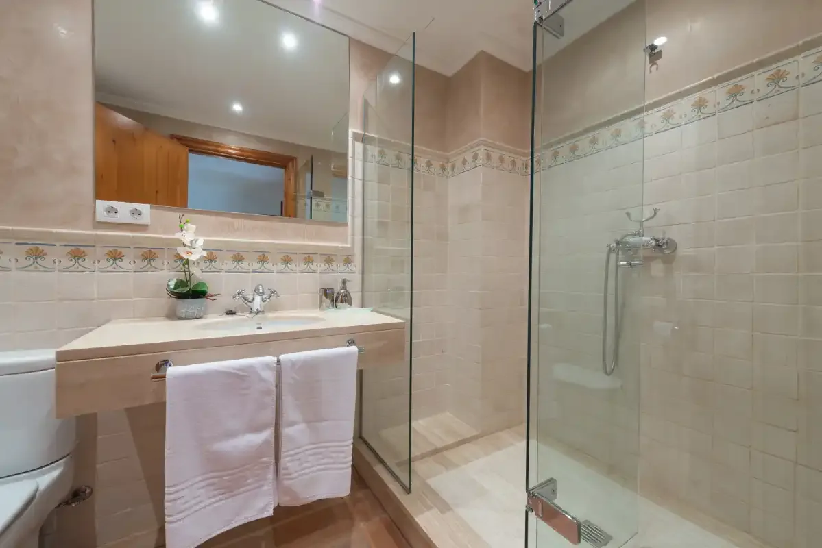 A tiled bathroom with a sink and glass-enclosed shower.