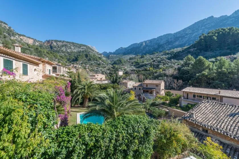 A village among green mountain slopes, with homes and a swimming pool.