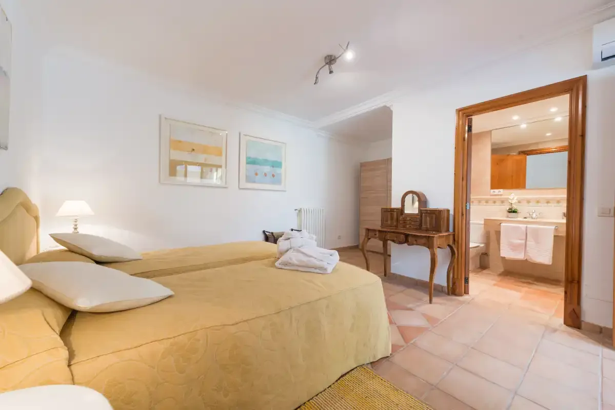 A bedroom with a yellow bed and an open doorway to a bathroom.