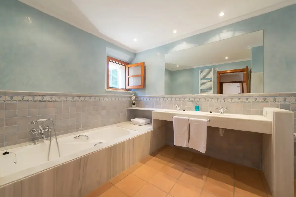 A tiled bathroom with a bathtub and a wide vanity beneath a mirror.